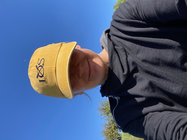 Photo of owner wearing a yellow cap that covers her eyes. Background is a perfectly blue sky