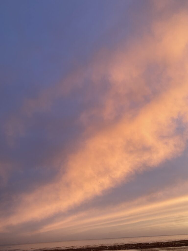 Beautiful coloured sky and clouds at sunset.  Sky is bluey purple and floating clouds have shades of pink, peach and yellow.