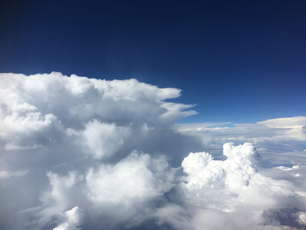 Cloud formations against a deep blue sky.  One of the clouds looks like a poodle dog 