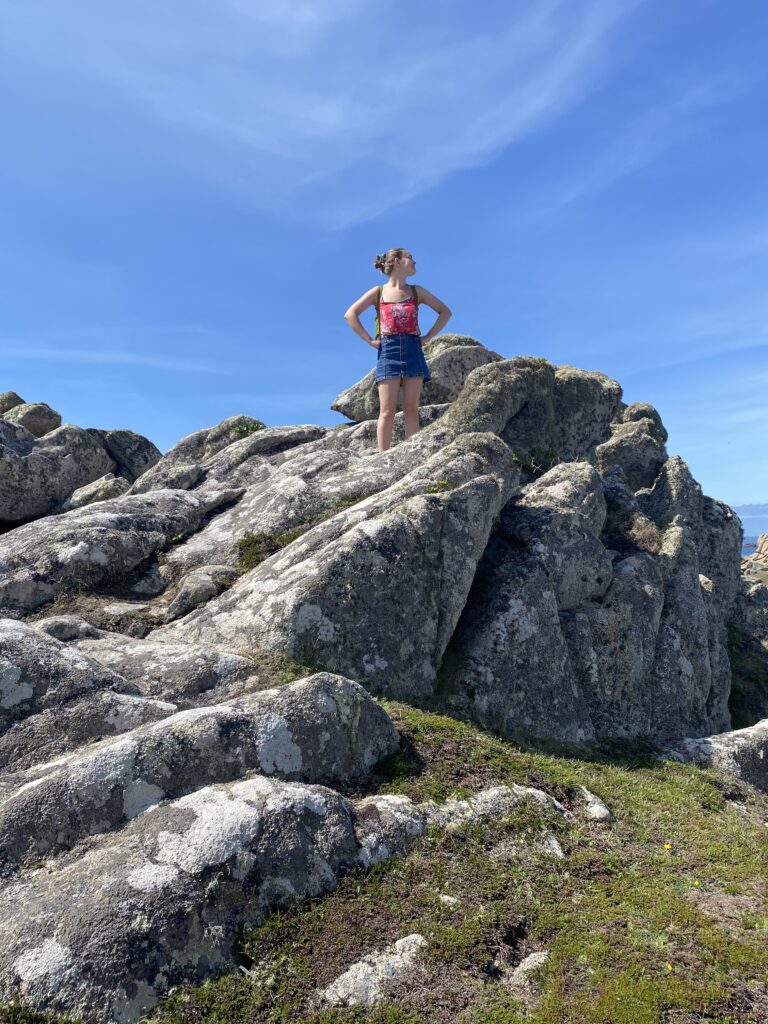 Young female human performing a power pose on top of very large rocks.  Life force energy is rule breaker